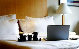 Hotel bed with laptop and breakfast tray