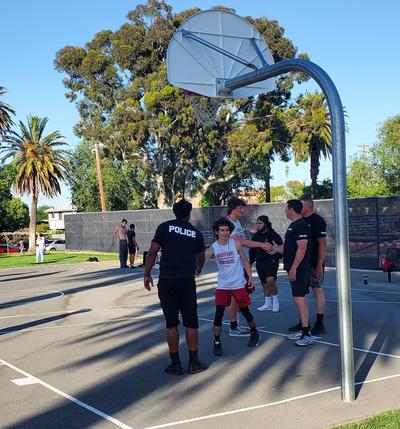 Police officers playing basketball with high school students and shaking hands